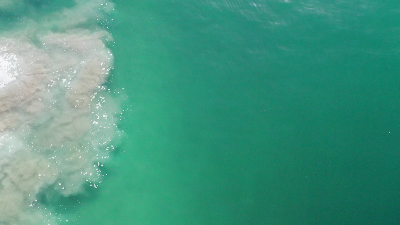 Turquoise water with pale reef rock at the upper left.