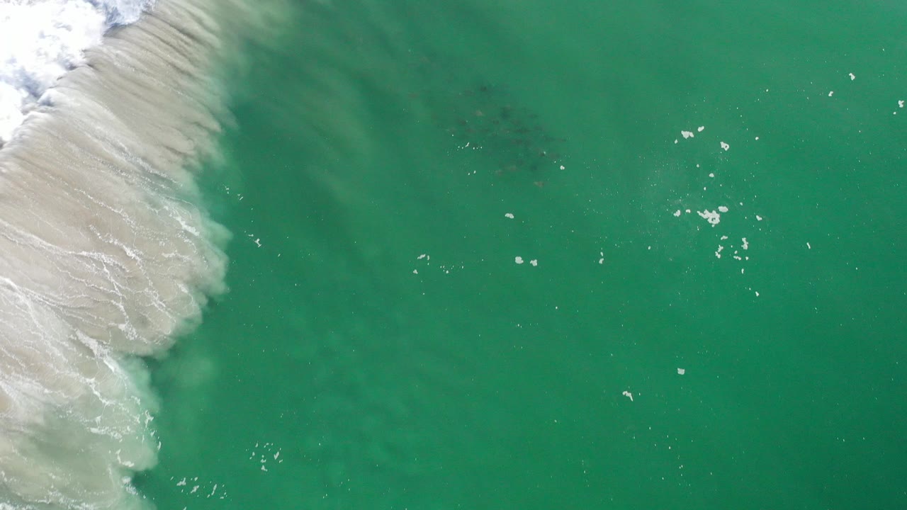 Overhead green ocean water with white surf along the upper left edge.