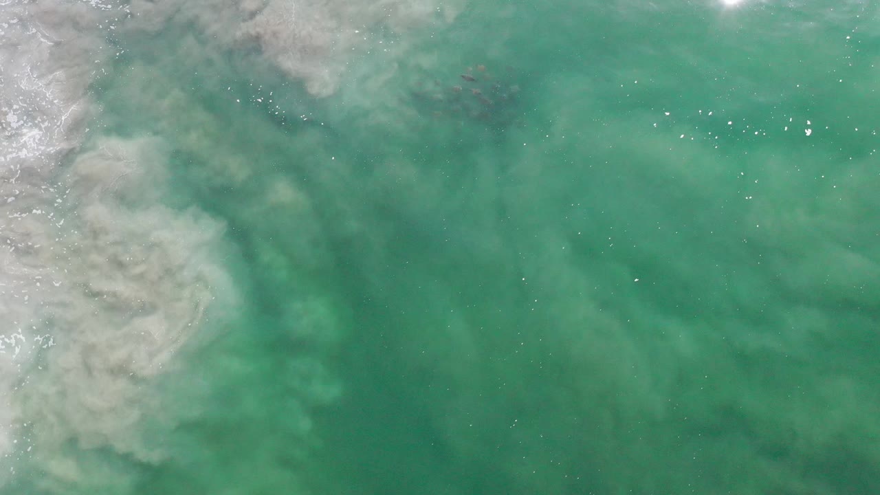 Turquoise green water with a pale turbulent band at left.