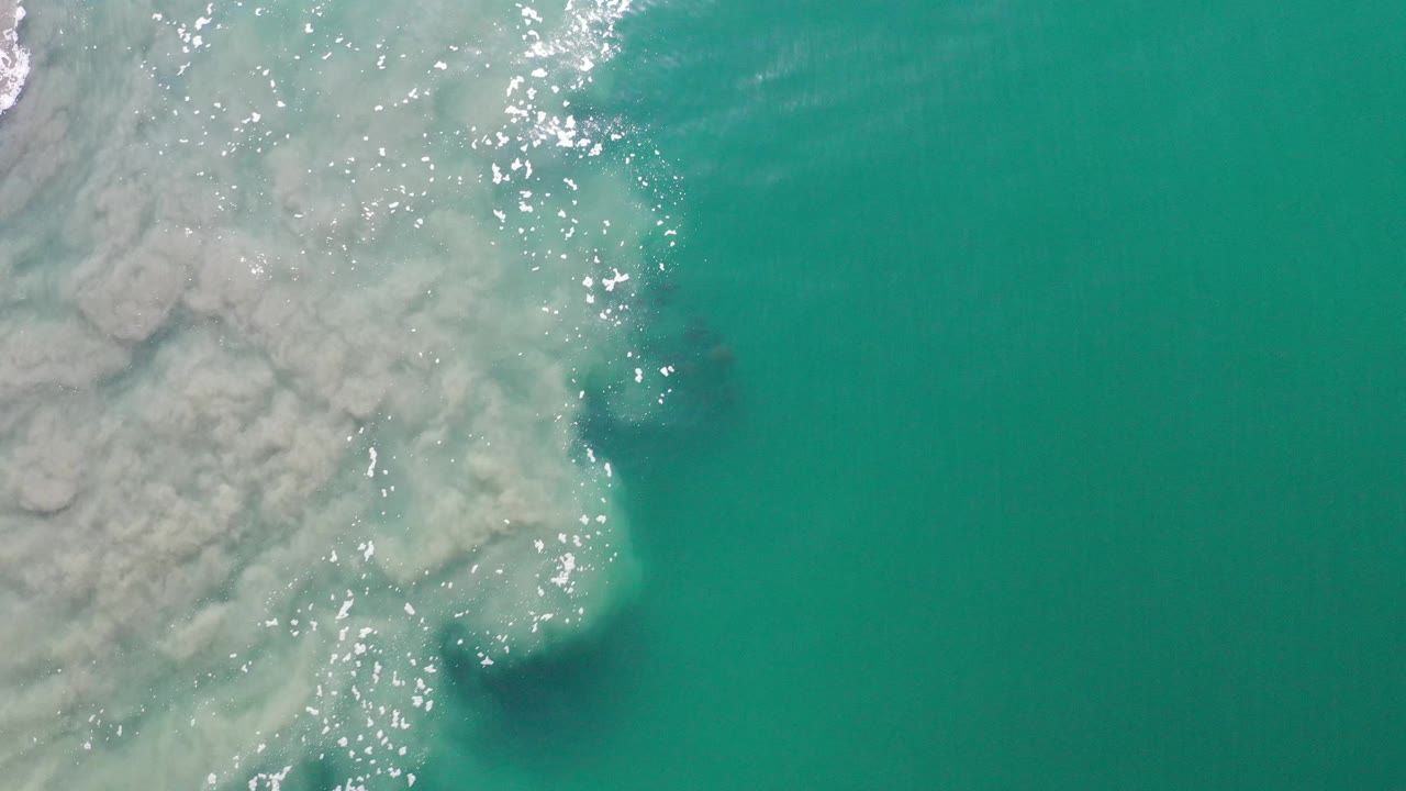 Aerial ocean surface with foam and bright sparkles.