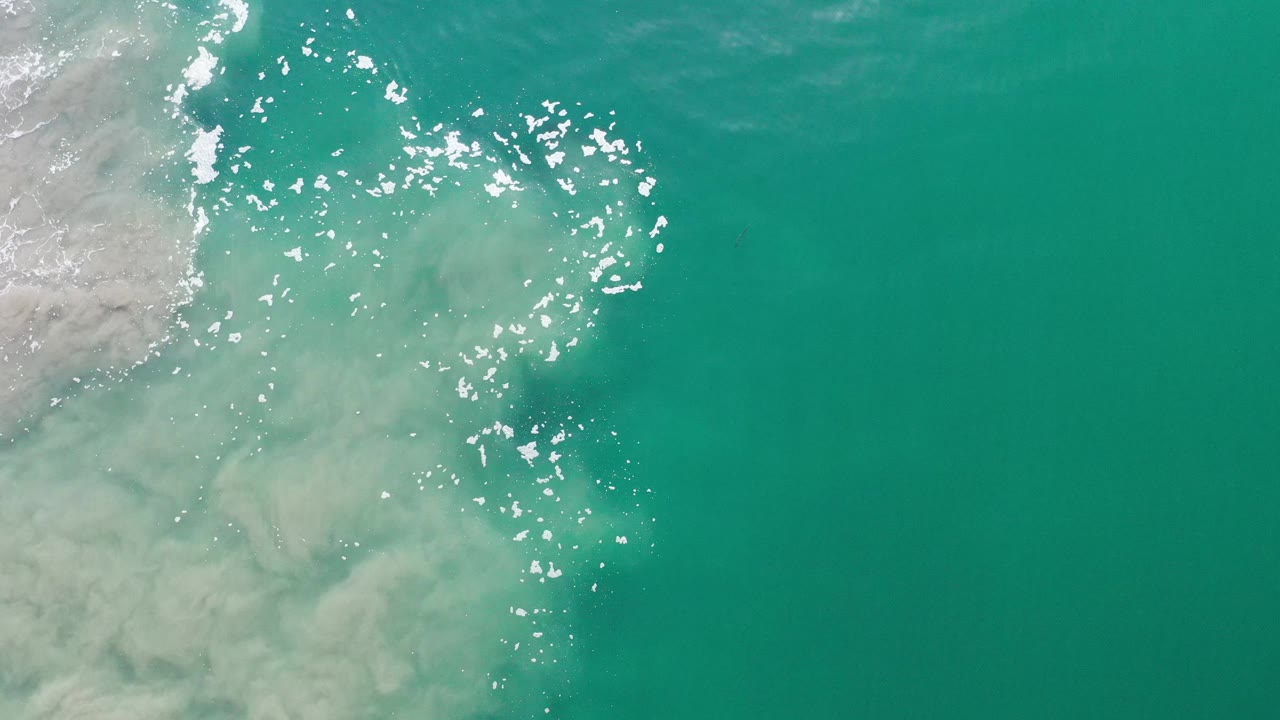 Pale sand mixing into clear turquoise ocean water