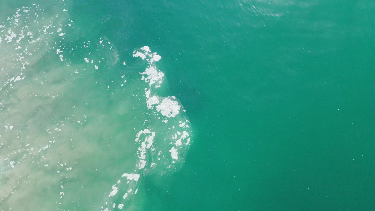 Turquoise ocean water with white foam near the left side.