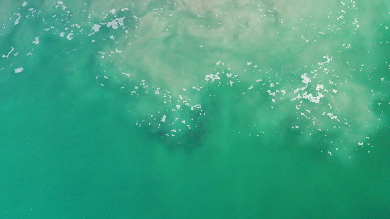 Overhead turquoise ocean water with pale foam near the top edge.