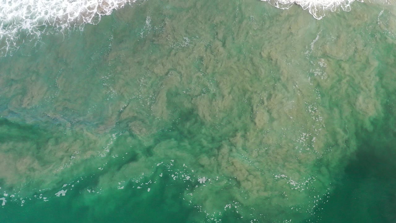Overhead green ocean water with white surf along the top edge