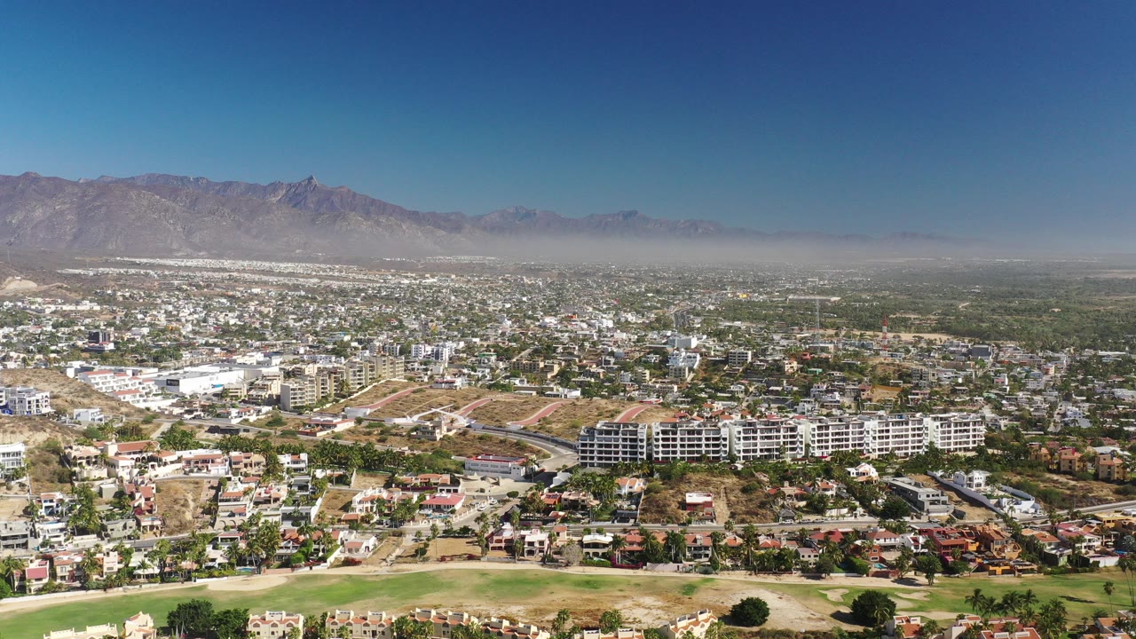 Wide aerial city view with mountains beyond.