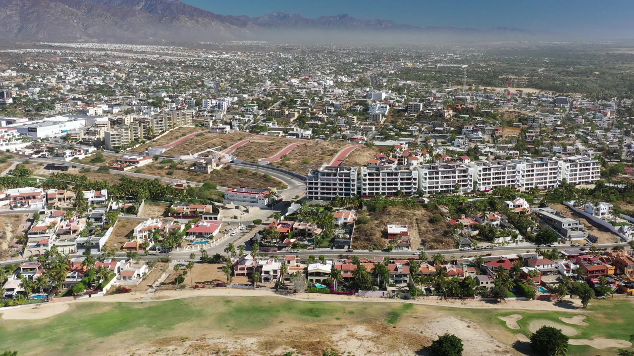 Aerial view of neighborhoods, green fields, and distant mountains.