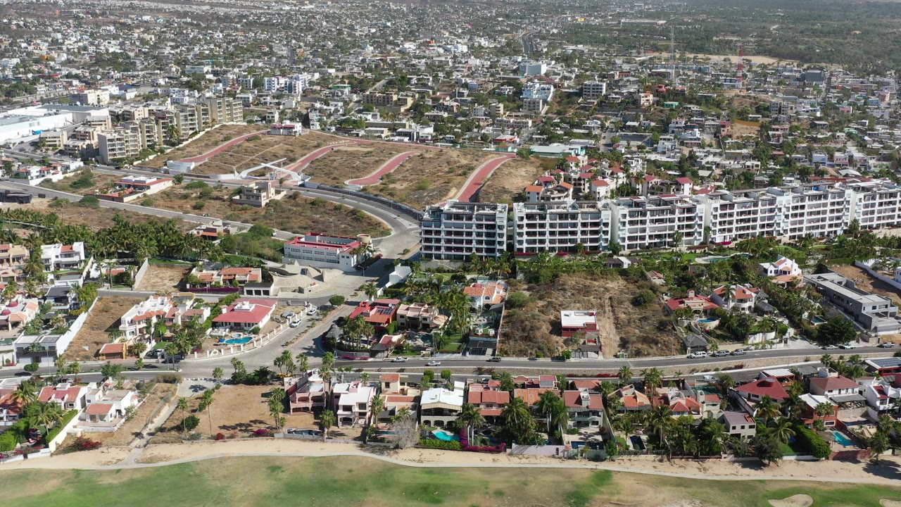 Aerial view of hillside roads, apartment blocks, homes, and a coastal edge.