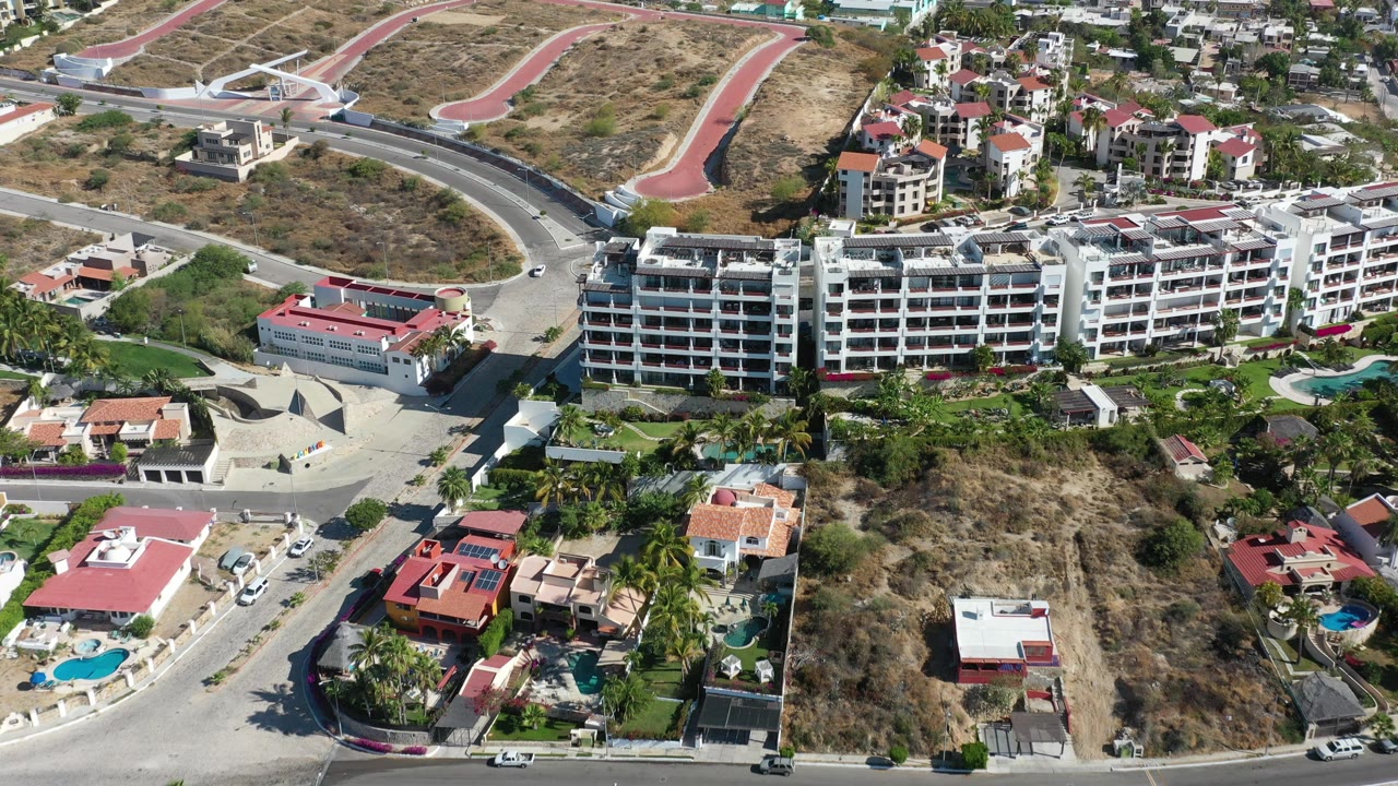 Aerial view of low-rise buildings, homes, roads, and dry hillside lots.