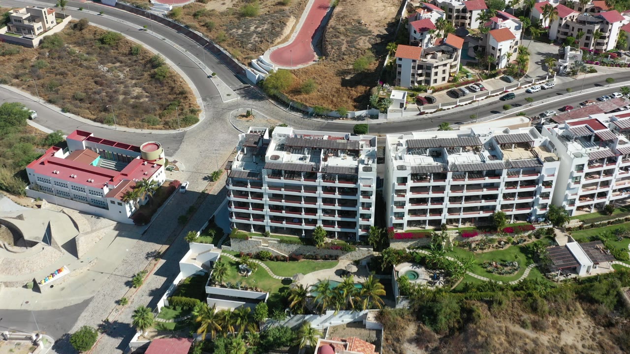 Aerial view of buildings beside a wide curved road and hillside lot.