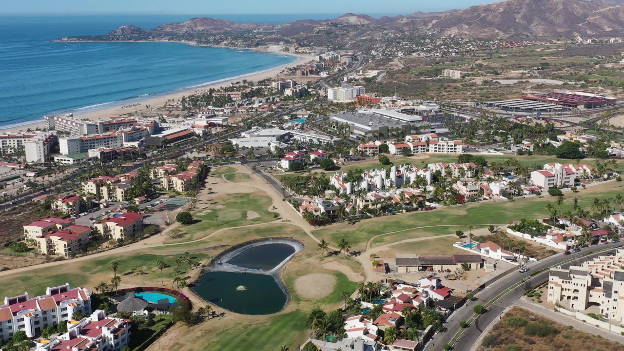 Aerial view of beach city, golf course, ponds, and ocean coastline.