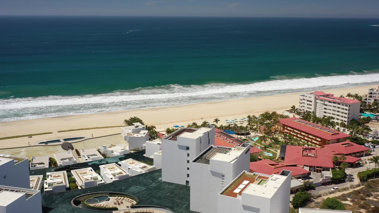 Aerial view of beachfront resort buildings, beach, and ocean surf.