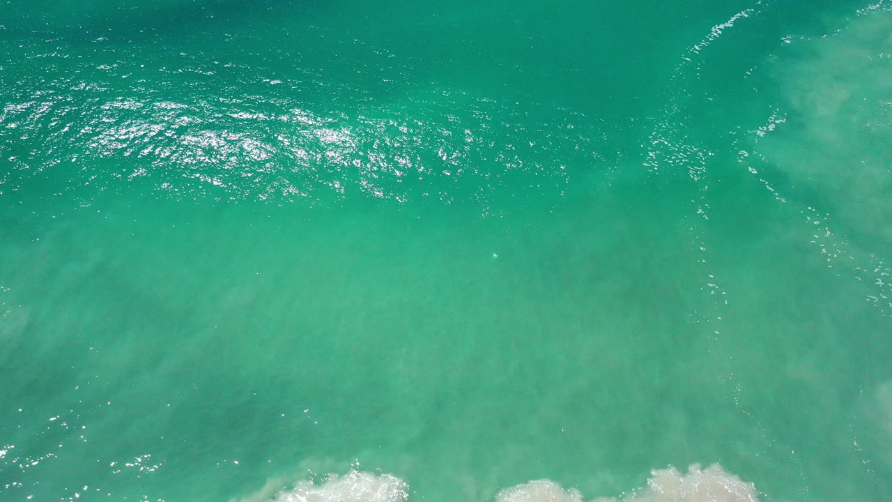 Overhead turquoise ocean water with pale underwater sand clouds.