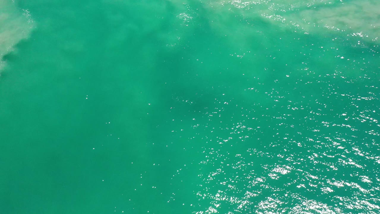 Open turquoise water with scattered sparkle and faint pale water at the top.