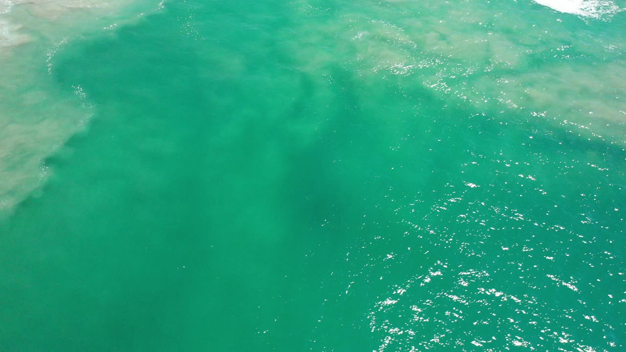 Turquoise ocean water with pale surf near the top edge.