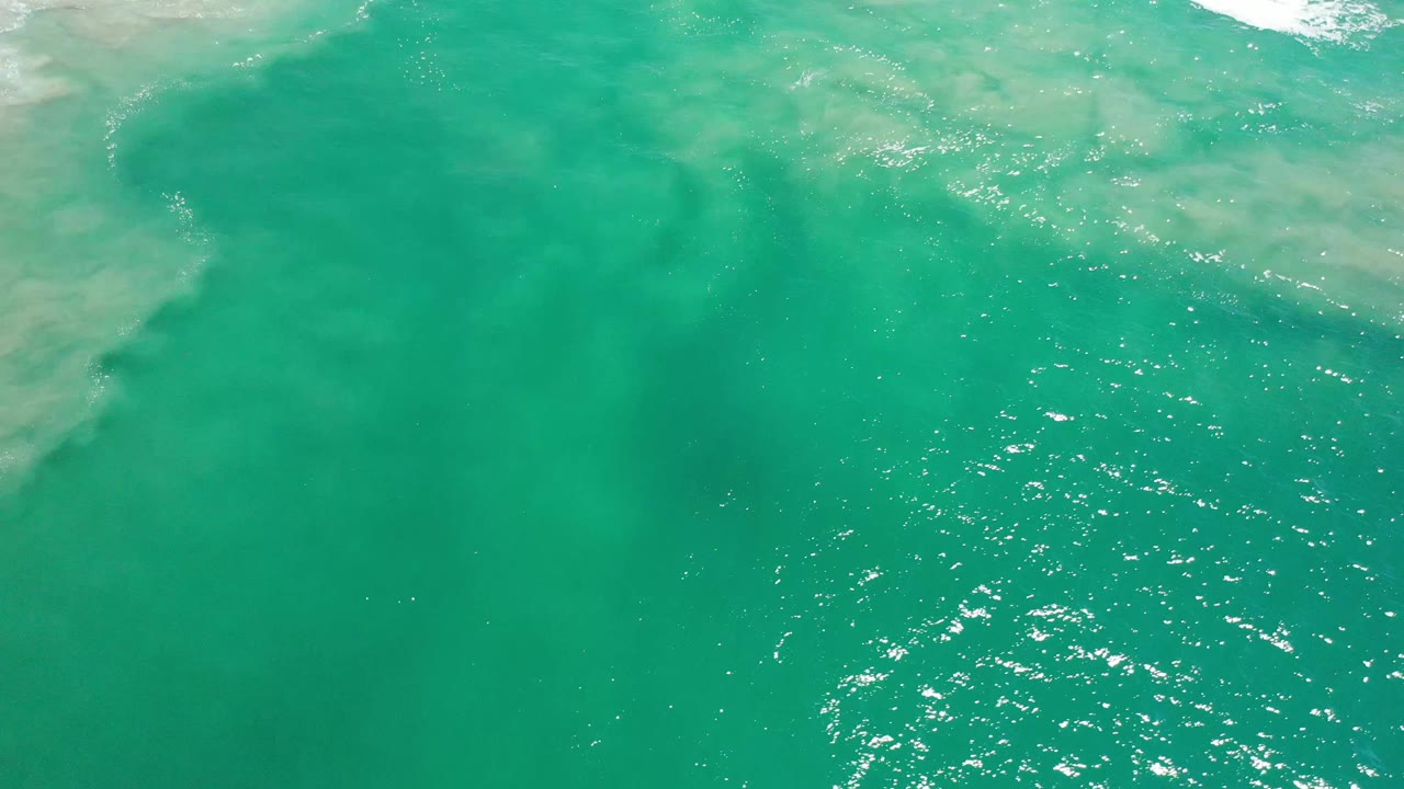 Overhead Los Cabos water view with green-blue color, faint sandy clouding under the surface, and no visible people.