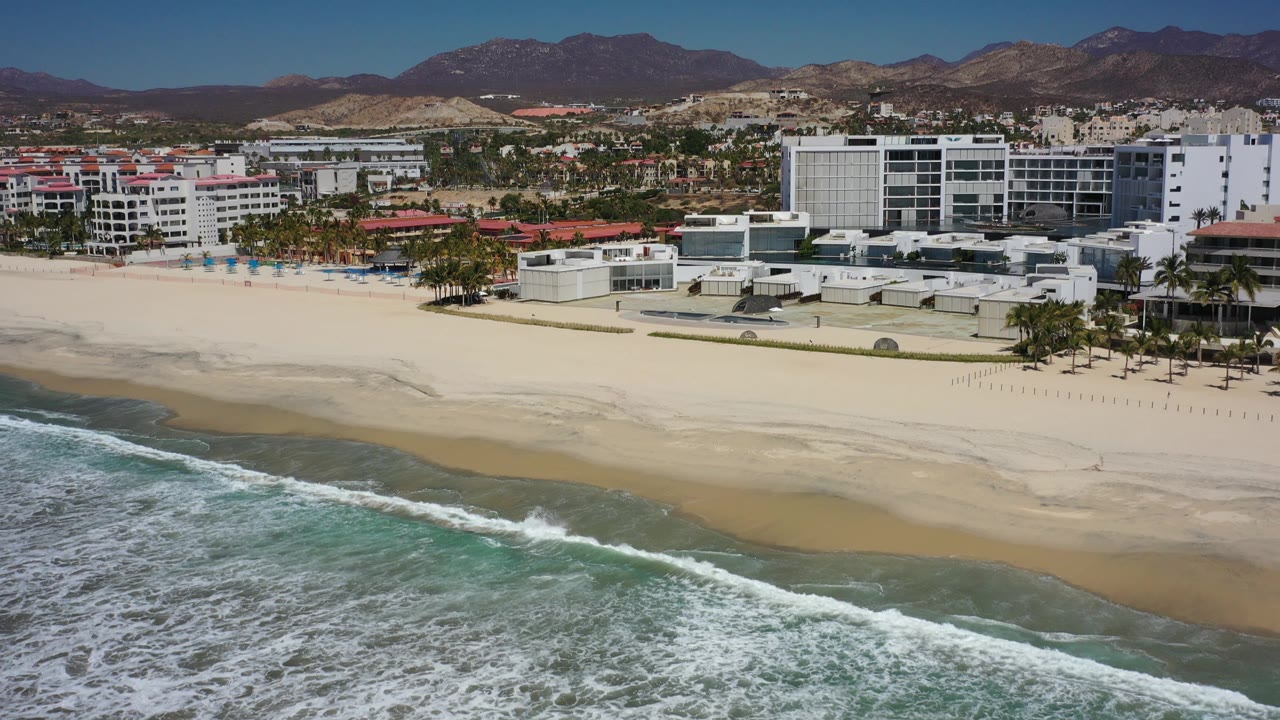 Wide beach, surf, beachfront hotels, city blocks, and mountains.