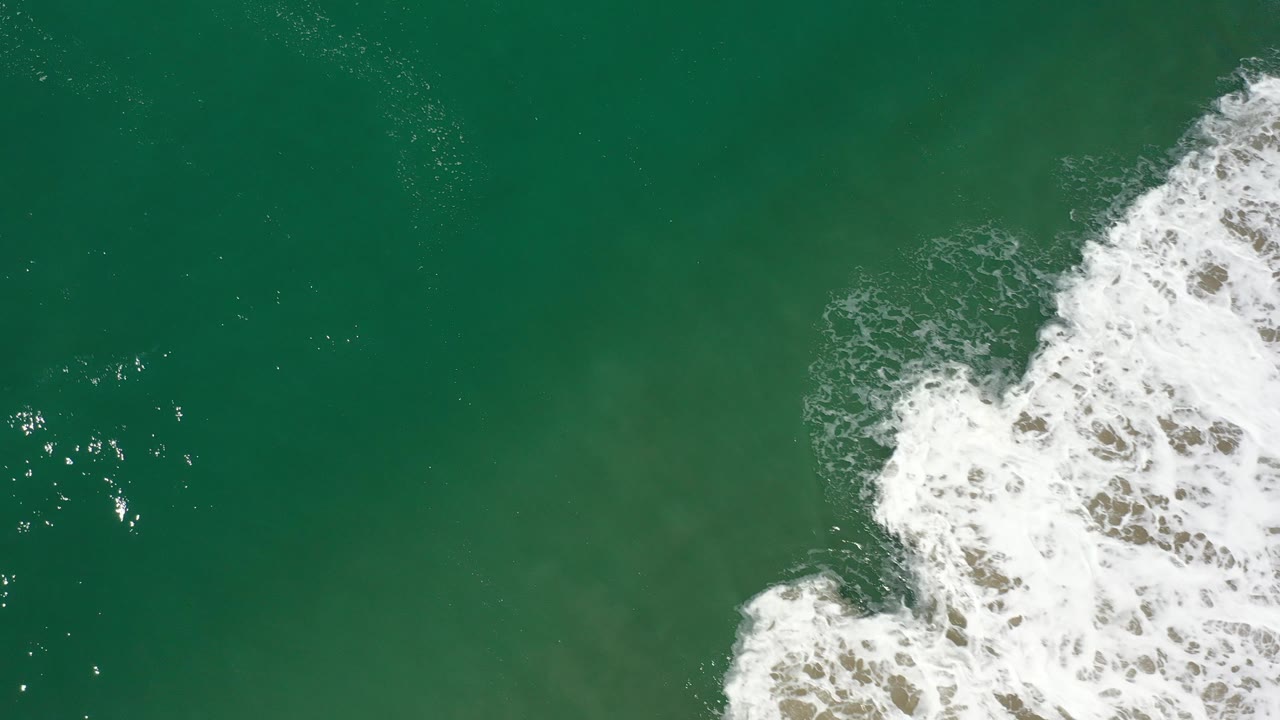 White surf breaks across the right side of green water