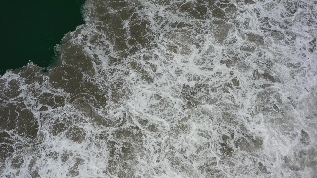 At 0:01, white foam fills more of the Los Cabos ocean view while darker water remains visible near the upper edge, with no visible people.