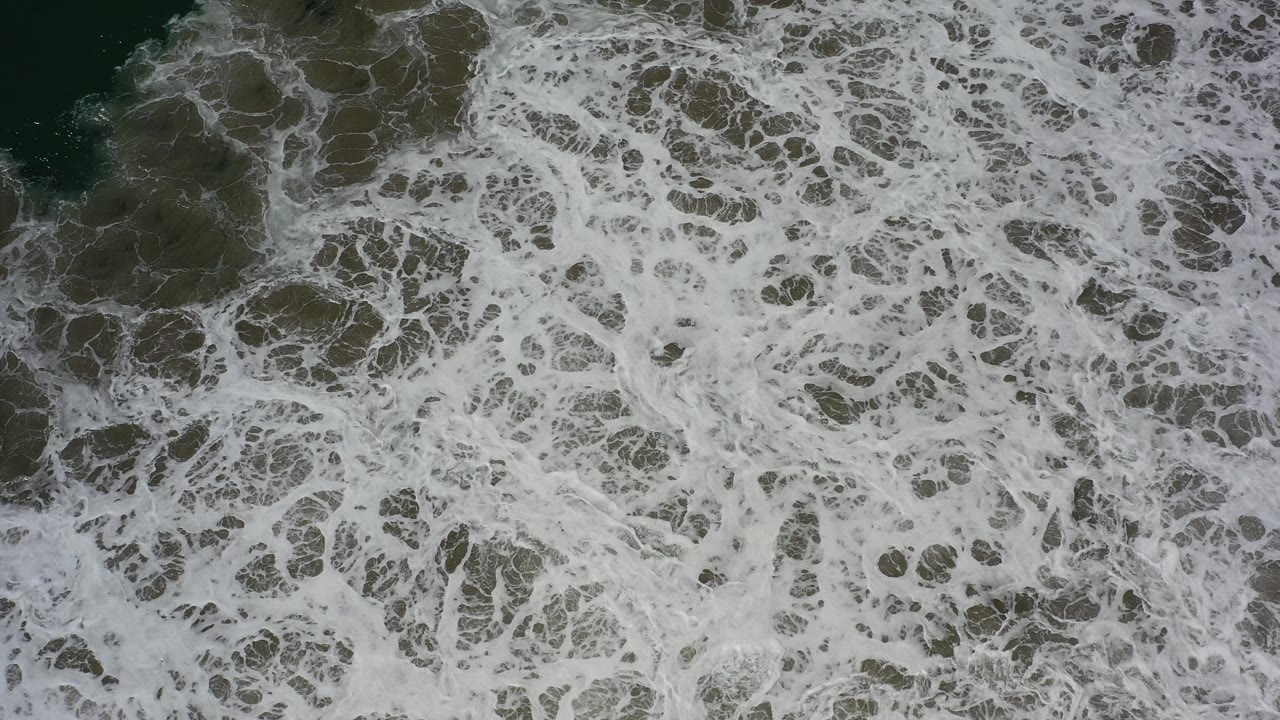 Overhead white surf covering dark rocks