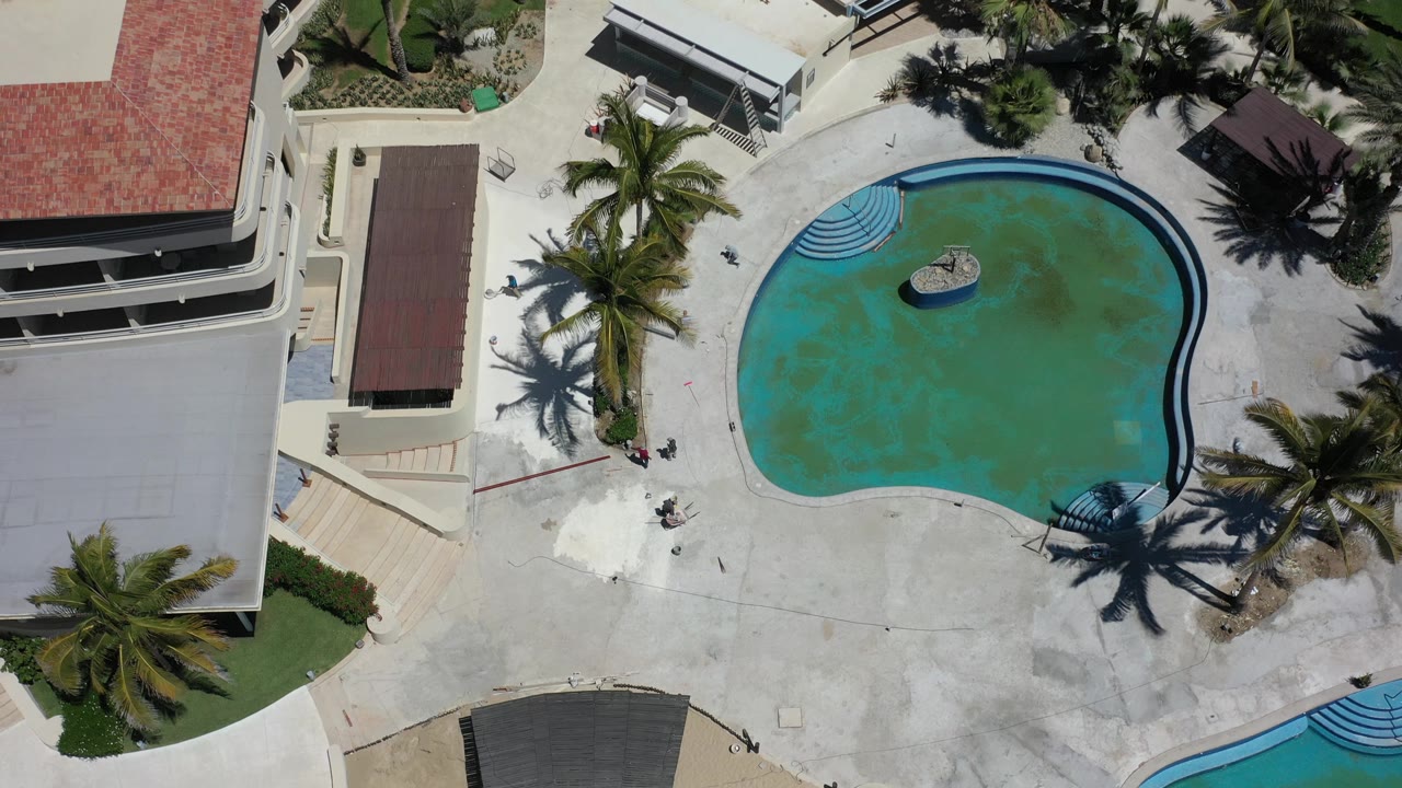 Top-down pool area with red roofs, palms, and patio deck.
