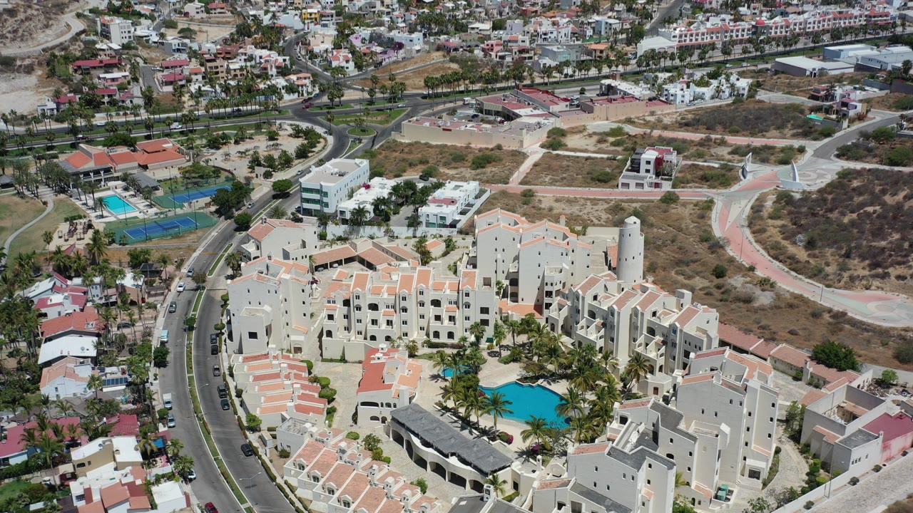 Aerial view of a resort complex with pool, roads, and hillside lots.