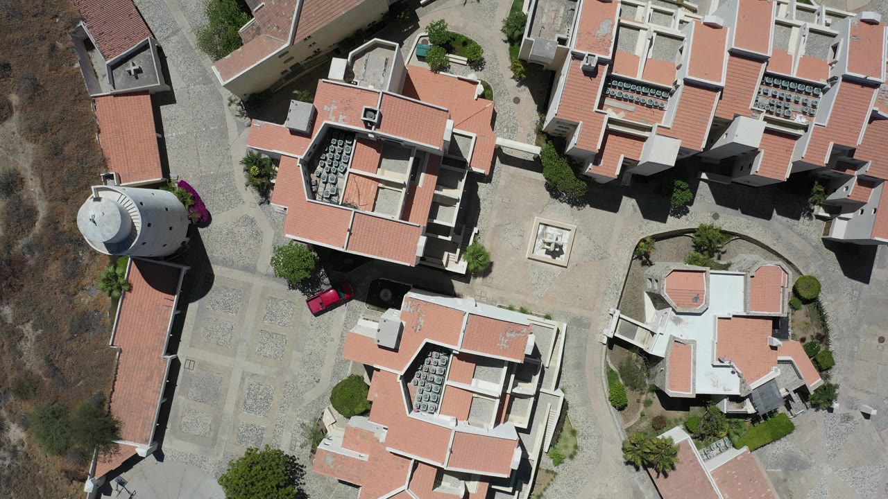 Overhead view of terracotta-roofed buildings and a round white tower.