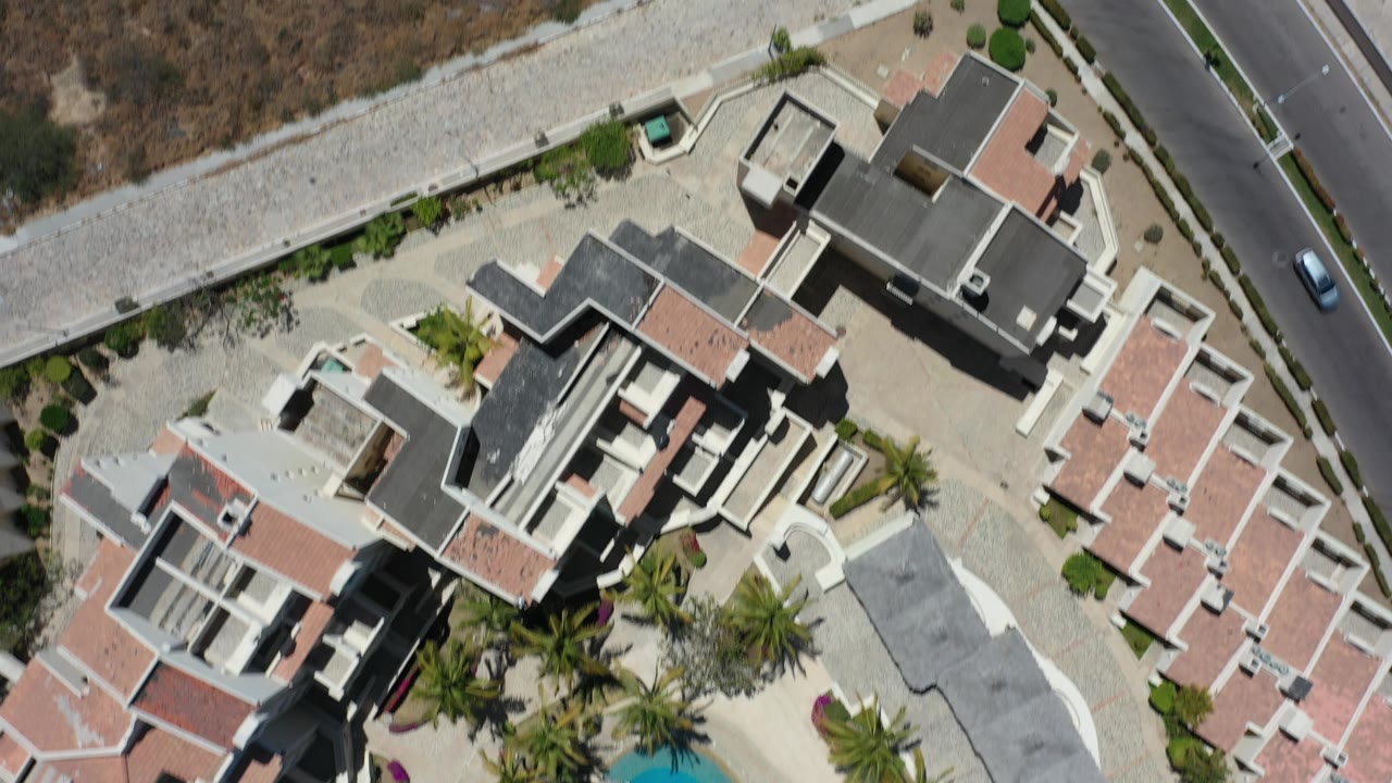 Overhead view of modern homes beside a road and dry scrubland.