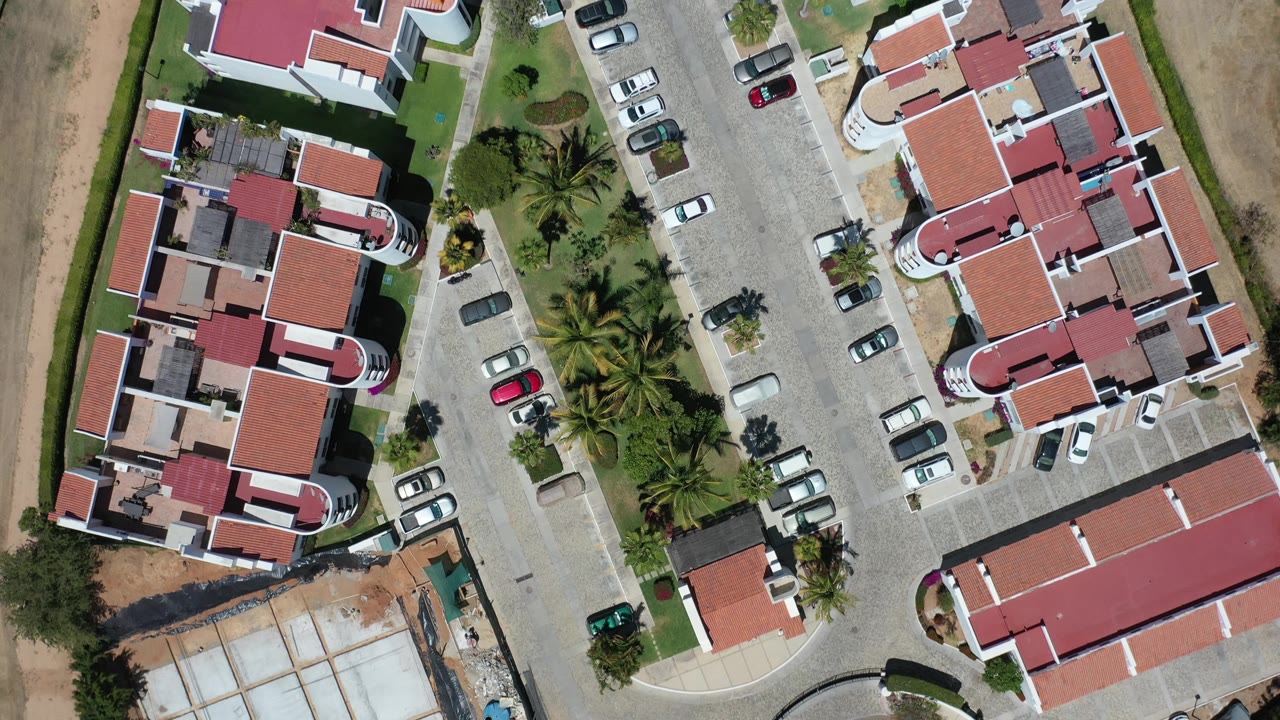 Overhead resort complex with red roofs, parking spaces, palms, and desert land.