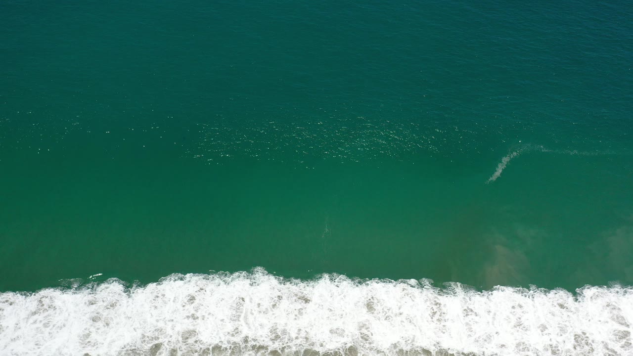 Overhead turquoise ocean with a white surf band near the bottom.