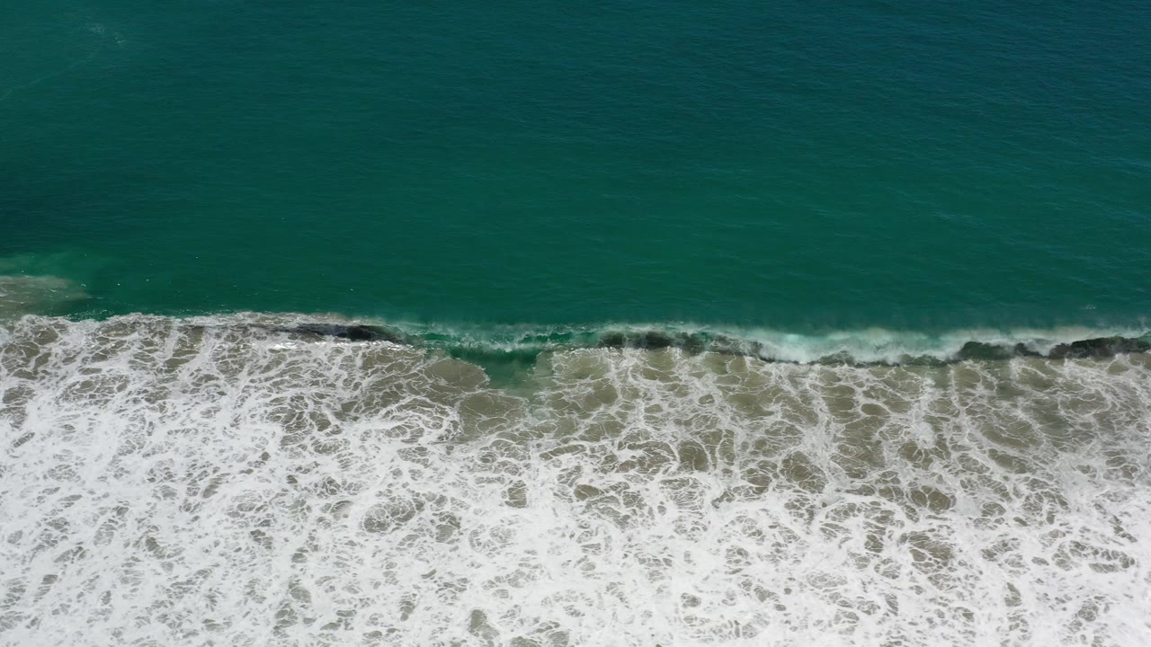 Foamy wave wash fills the lower frame below green ocean water.
