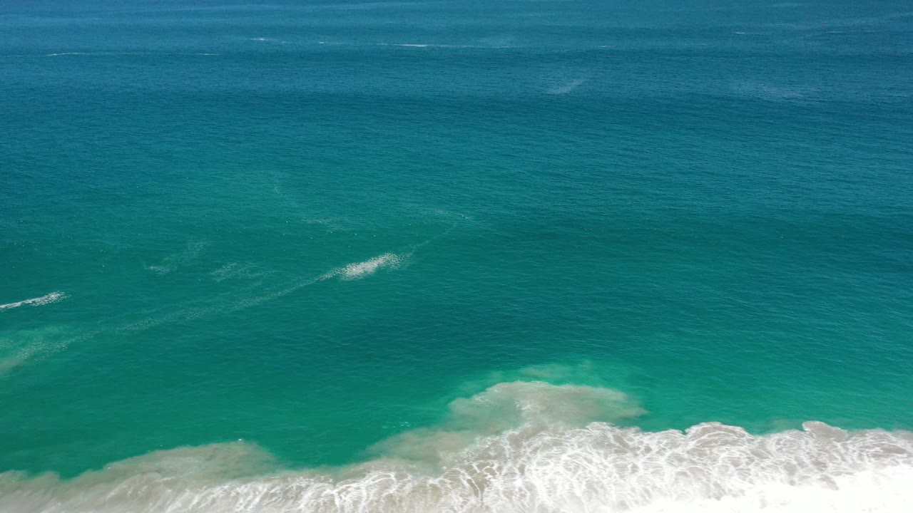 Open turquoise water with surf breaking across the lower right.