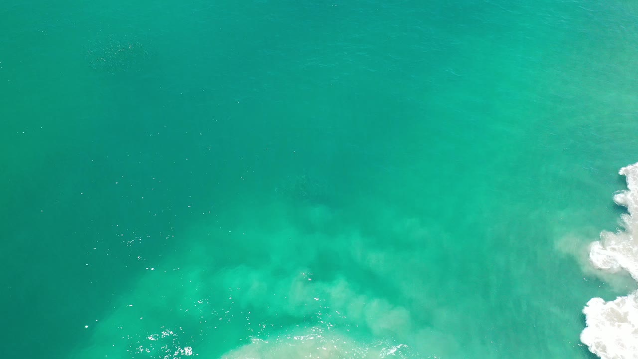 Overhead teal ocean with white surf at the right edge.