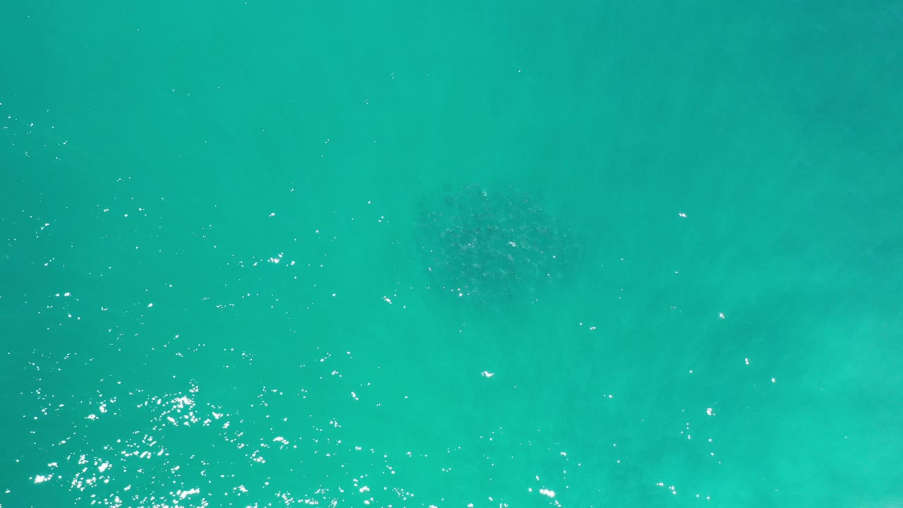 Clear turquoise water with faint submerged shapes and light surface texture.