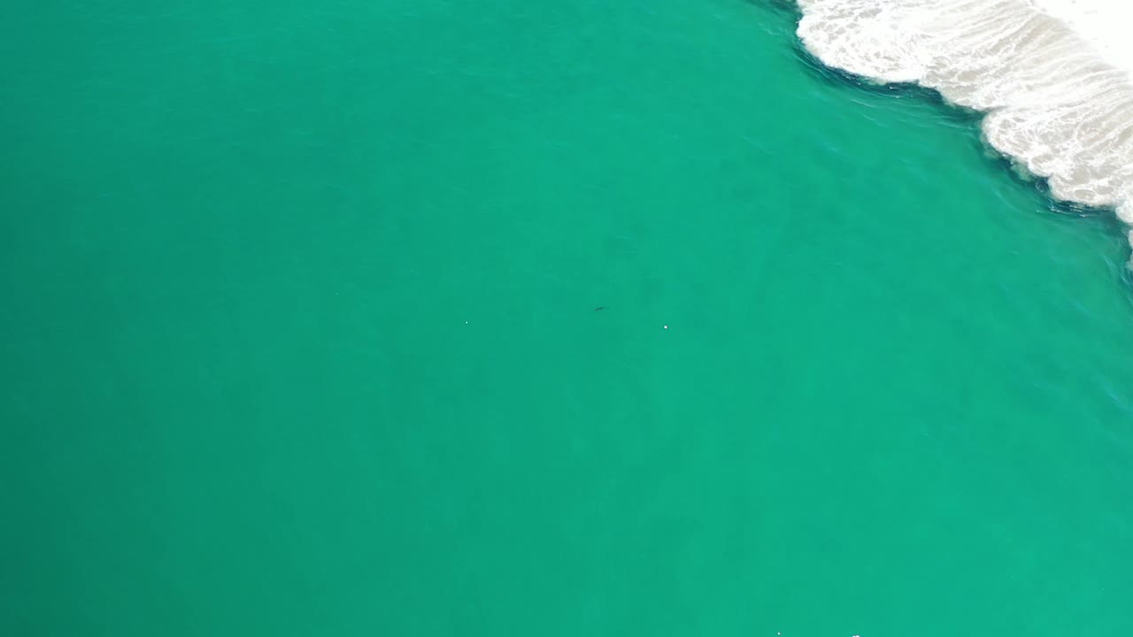 Aerial-looking frame of teal Los Cabos ocean with a brighter strip of white wave foam along the upper right and no visible people.