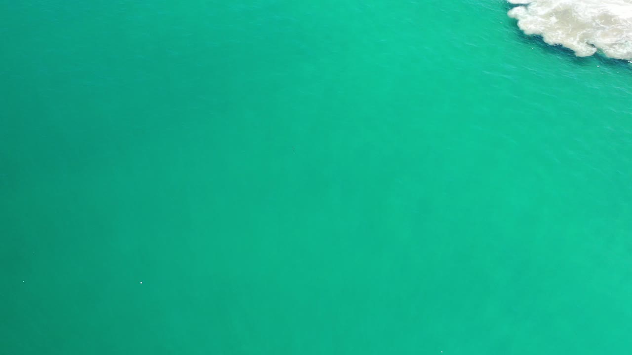 Overhead turquoise water in Los Cabos, Mexico, with white surf clipped into the upper right corner and no visible people.