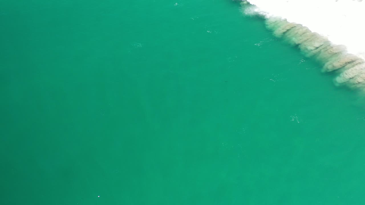 Overhead green ocean water with white surf along the upper right edge.