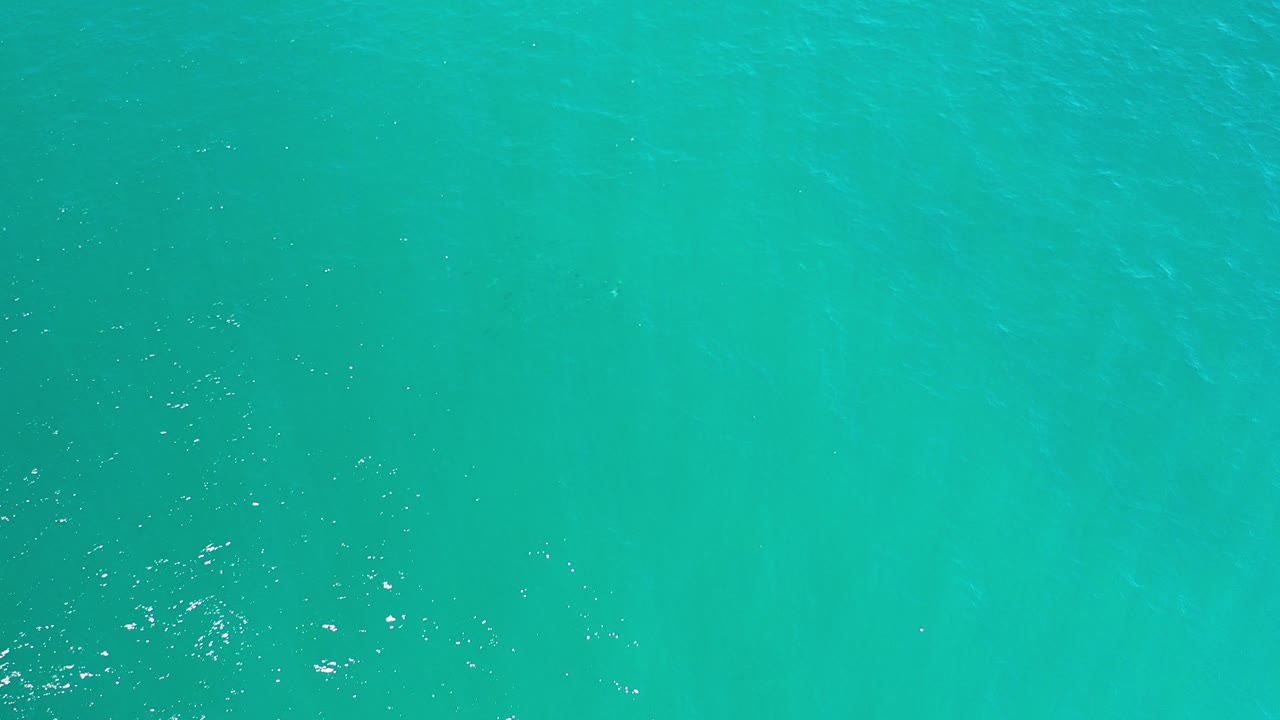 Overhead view of turquoise ocean water in Los Cabos, Mexico, with faint darker bands beneath the surface and no visible people.