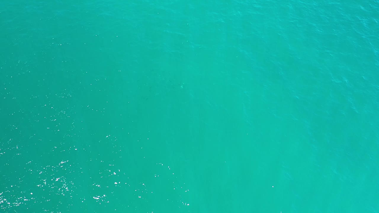Aerial frame of blue-green sea surface in Los Cabos, Mexico, with scattered white glints and no visible people.