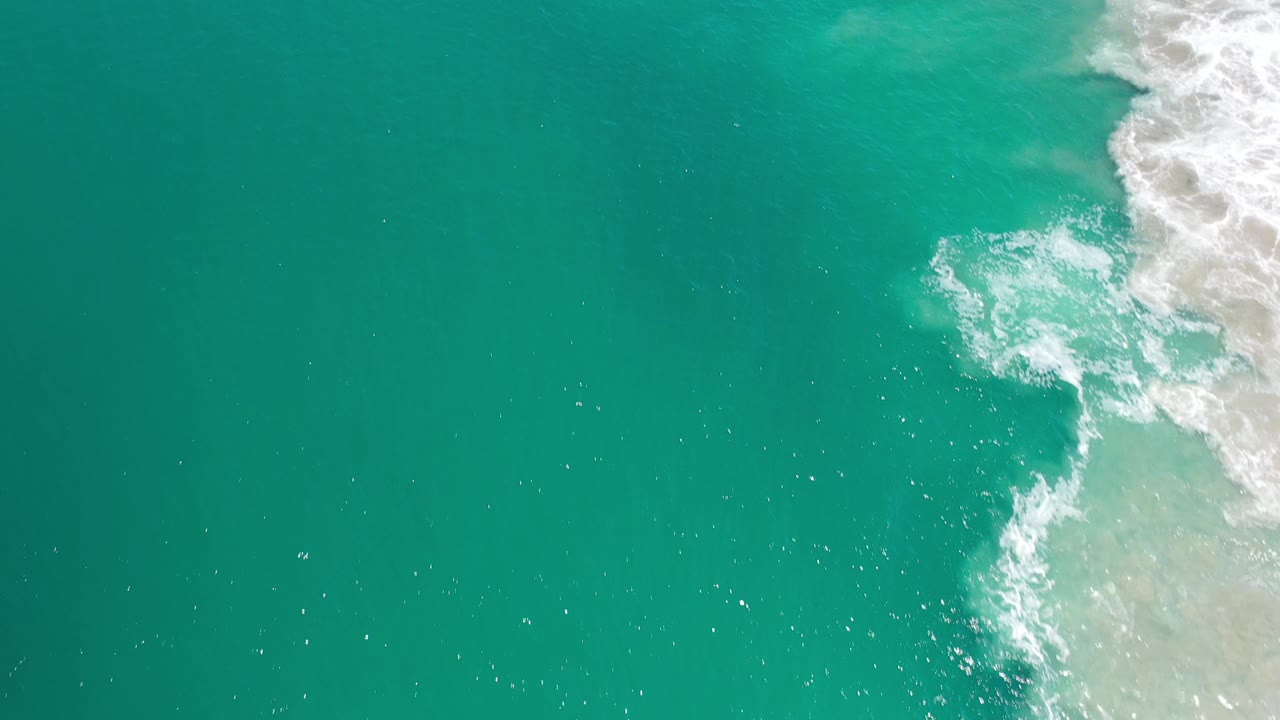 Open turquoise water with surf foam near the upper right.