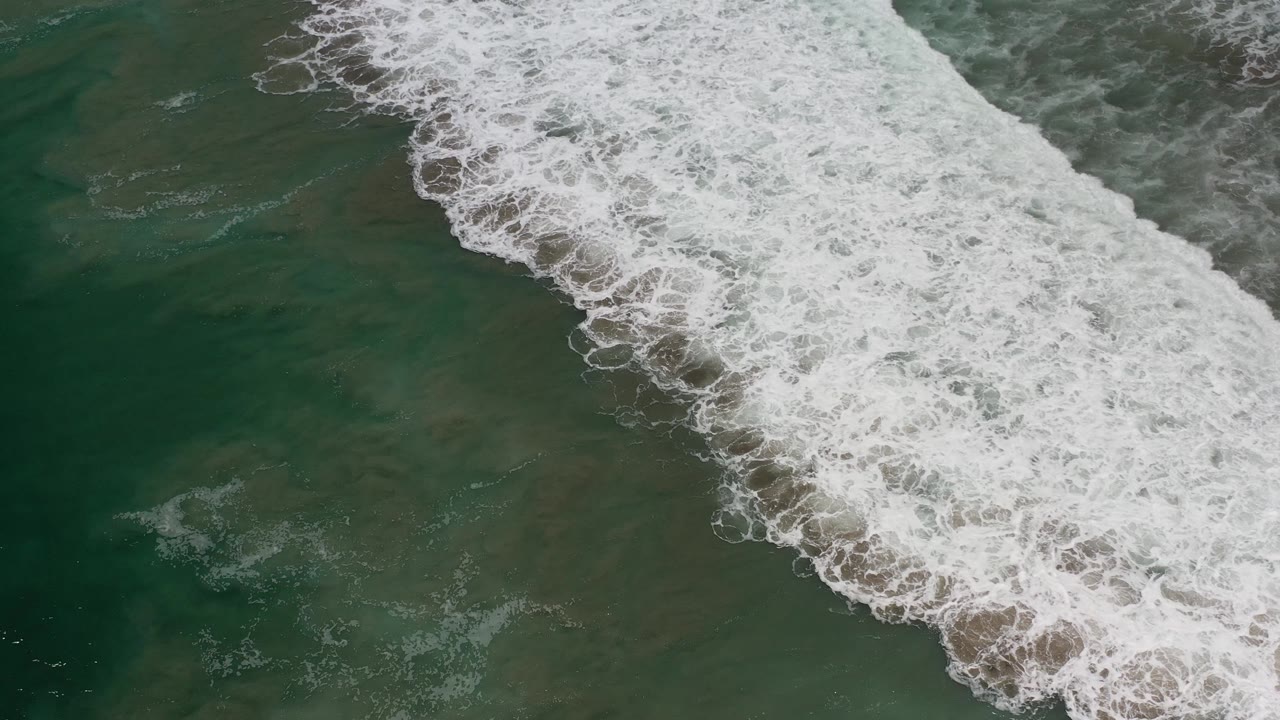Diagonal whitewater across translucent green sea