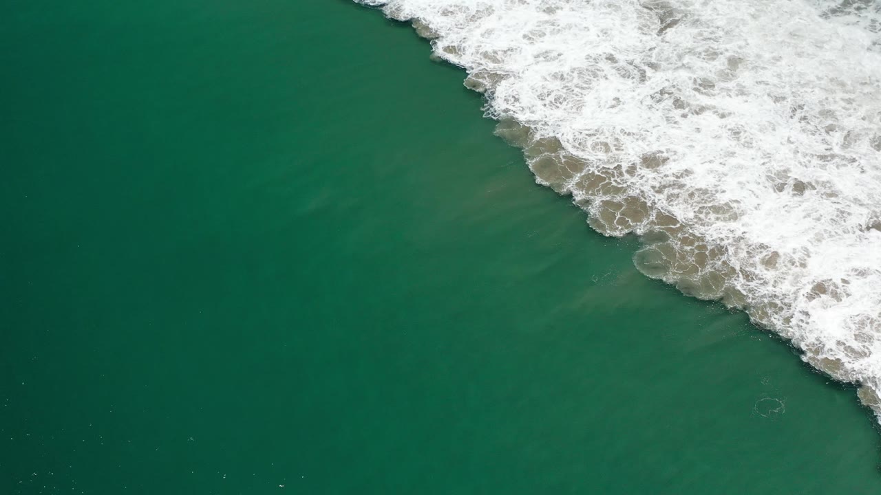 White surf foam crossing the top right of green water.