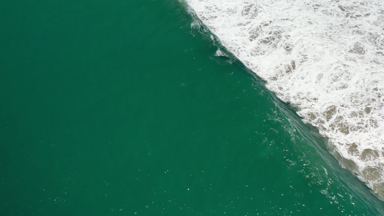Open teal water with foamy wave edge at the upper right