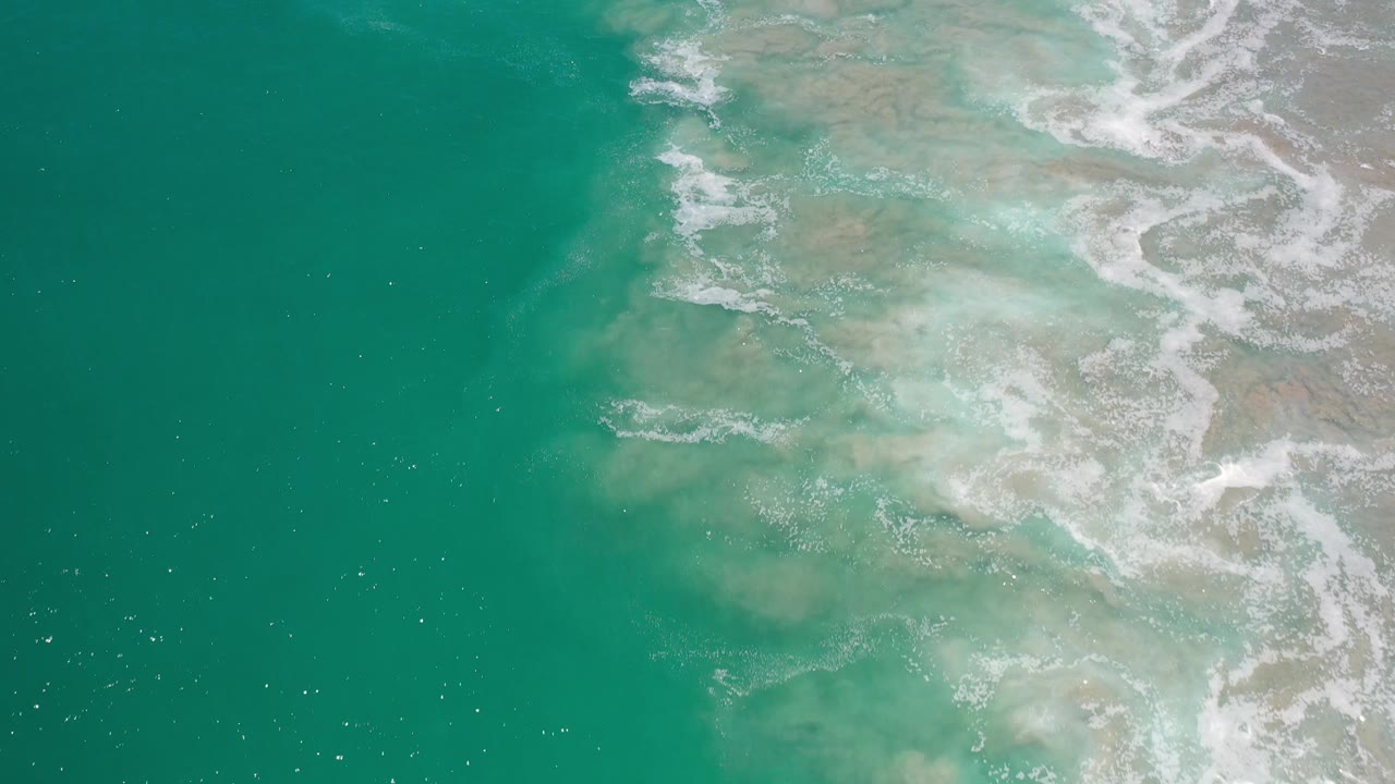 Deep turquoise ocean with foam over shallow patches.