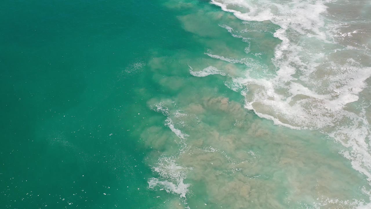 Clear green water with foam trails and pale rocks beneath the surface.