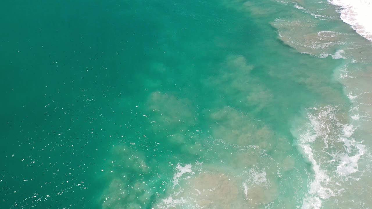Turquoise ocean water with white surf at the right edge.