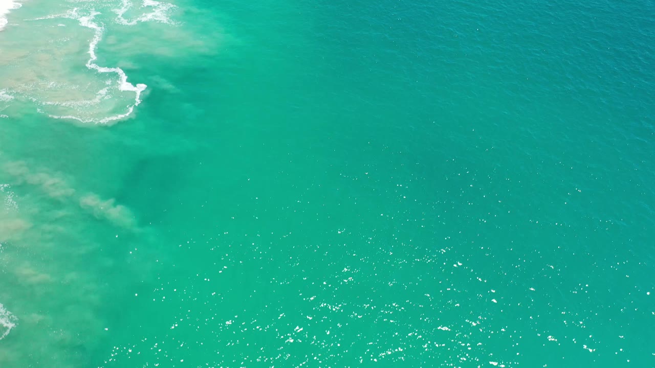 Turquoise sea in Los Cabos, Mexico, with a milky patch of nearshore water on the left and open darker water to the right, no visible people.