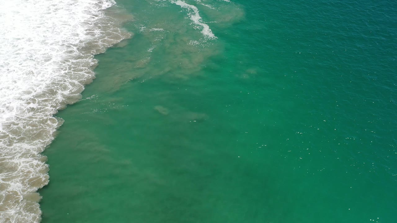 Foamy shoreline water beside darker green ocean