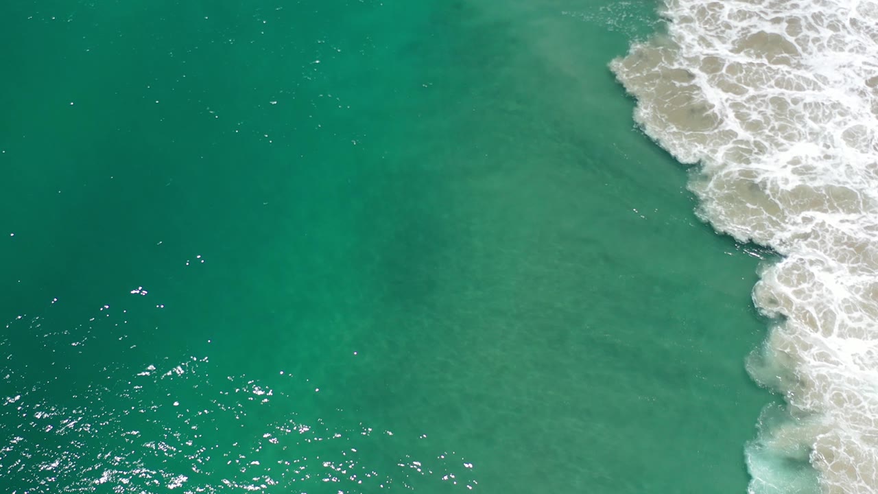 Turquoise sea with a narrow band of breaking foam at the upper right.