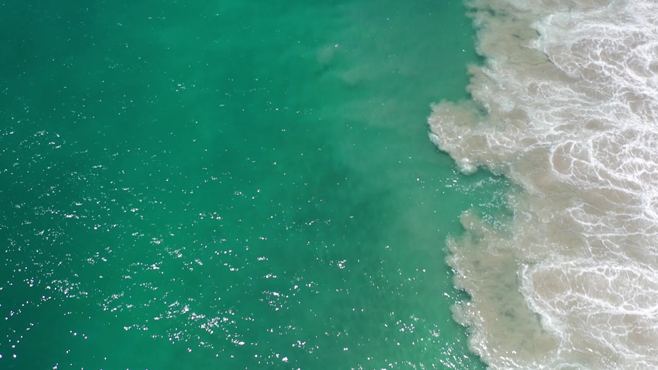 Open teal ocean beside churning white wave foam