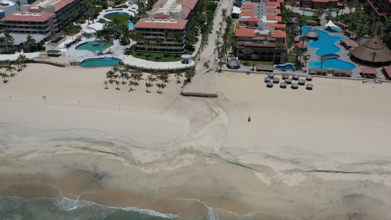Aerial view of beachfront hotels, pools, sand, and surf.